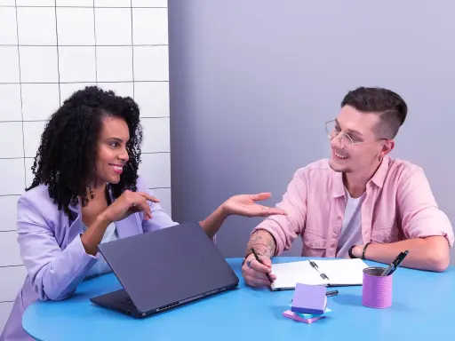 Imagem de um homem e uma mulher conversando em uma sala de reunião.