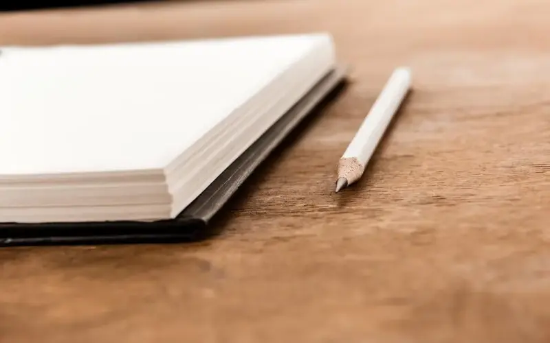 Imagem de um caderno e um lápis
