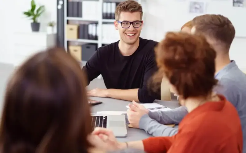 Imagem de diversas pessoas em uma sala de reunião conversando e sorrindo