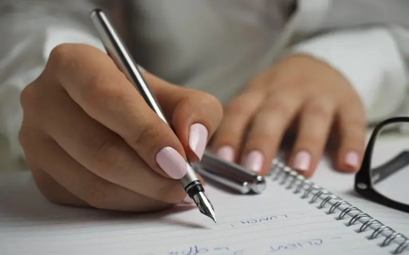 Imagem de uma pessoa preenchendo notas em um caderno