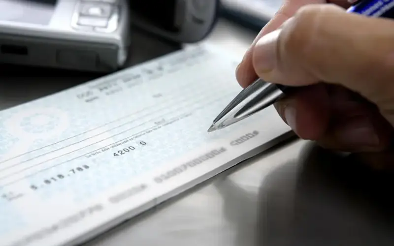Imagem de uma pessoa preenchendo um cheque