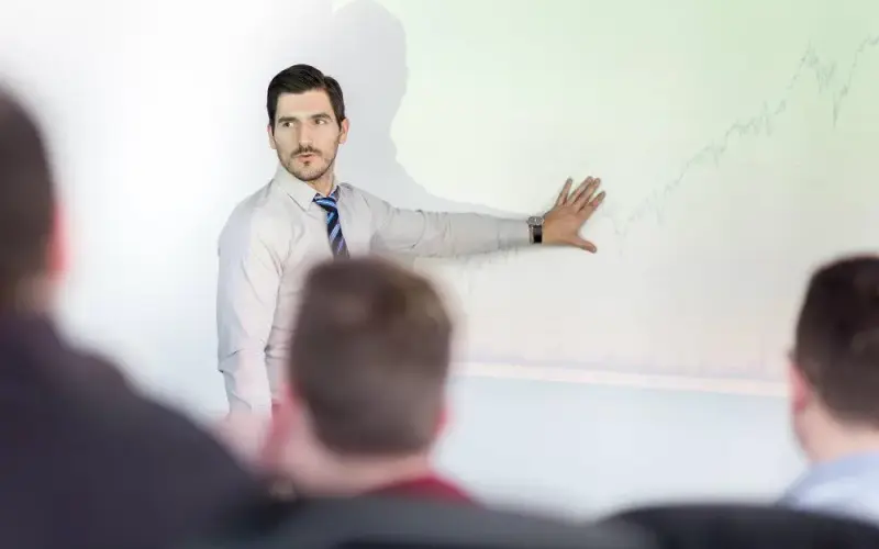 Imagem de um homem de terno dando uma palestra sobre contratação