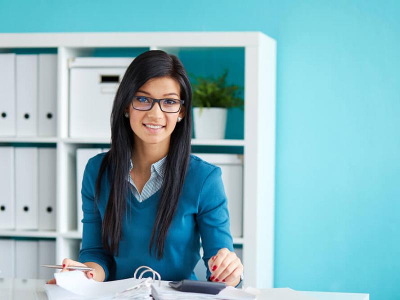Imagem de uma mulher em um escritório calculando o custo da folha